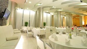 A spacious banquet hall with round tables set for dining, a reception area with a sofa, and a television mounted on the wall. - Mayflower Grande Hotel Hat Yai (Hat Yai)