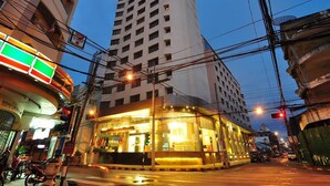 A multi-story building with a prominent corner entrance, surrounded by other buildings and visible power lines. - Mayflower Grande Hotel Hat Yai (Hat Yai)