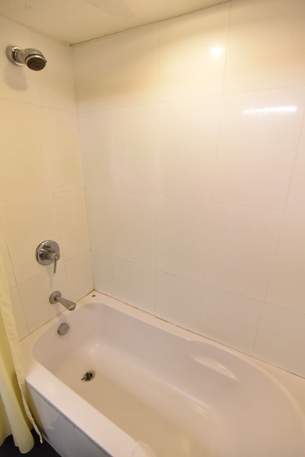 A bathroom with a bathtub, a showerhead, and a toilet.