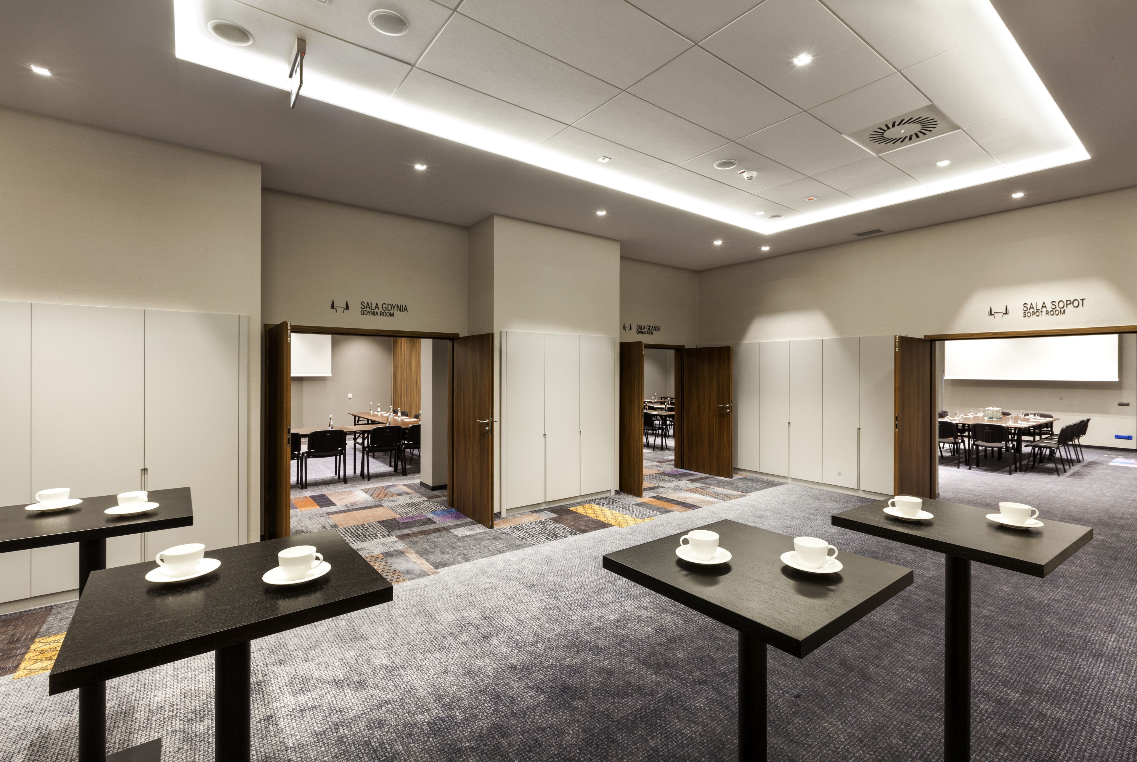 En hotellobby med flera sittgrupper, ett konferensrum och en receptionsdisk.