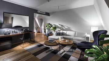 A modern living room with a sofa, two coffee tables, a desk with a chair, and a large mirror.