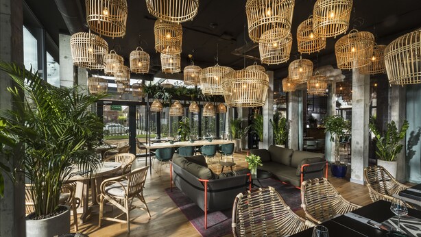 A modern interior with wicker furniture, a dining area, and hanging wicker light fixtures. - Hotel Sadova (Gdansk)