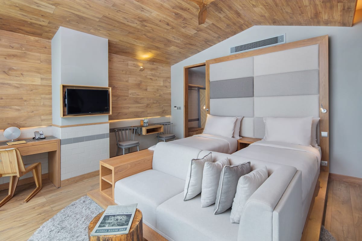 A modern hotel room with a large bed, a desk, and a TV mounted on the wall.