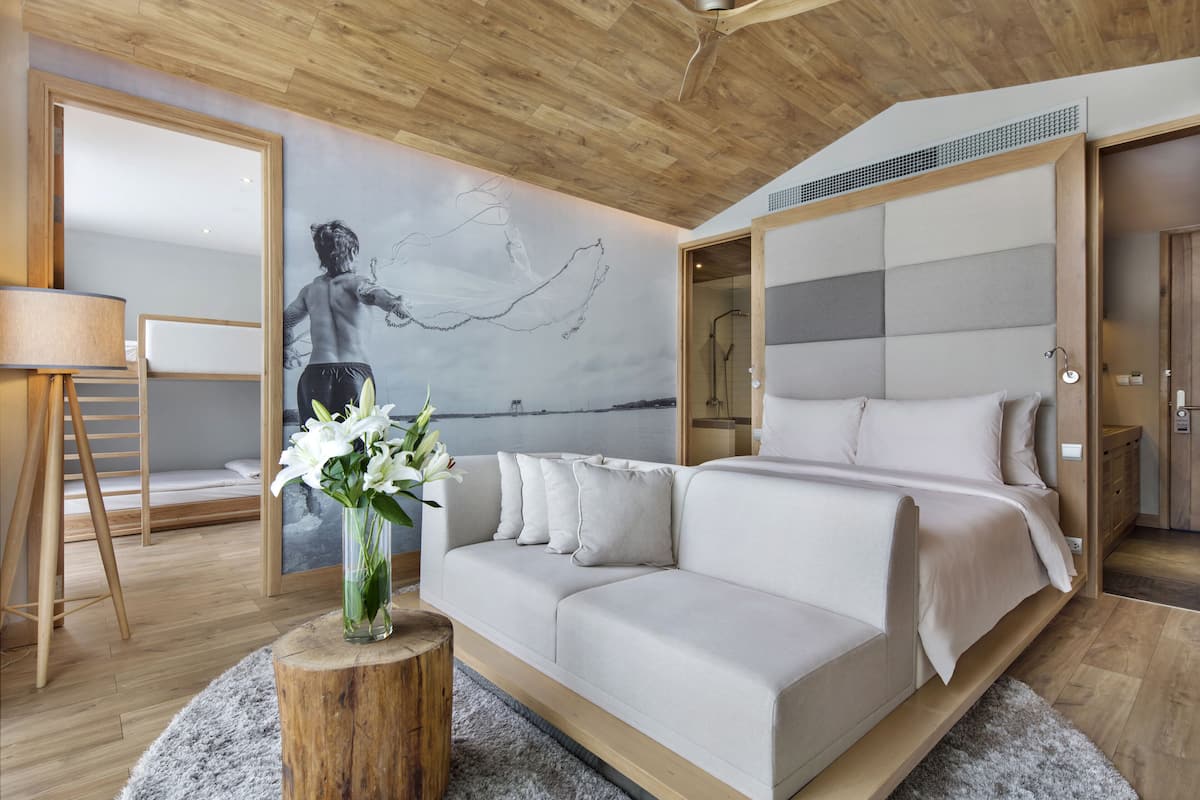 A modern bedroom with a large bed, a sofa, a wooden floor, a wooden ceiling, and a wall mural.