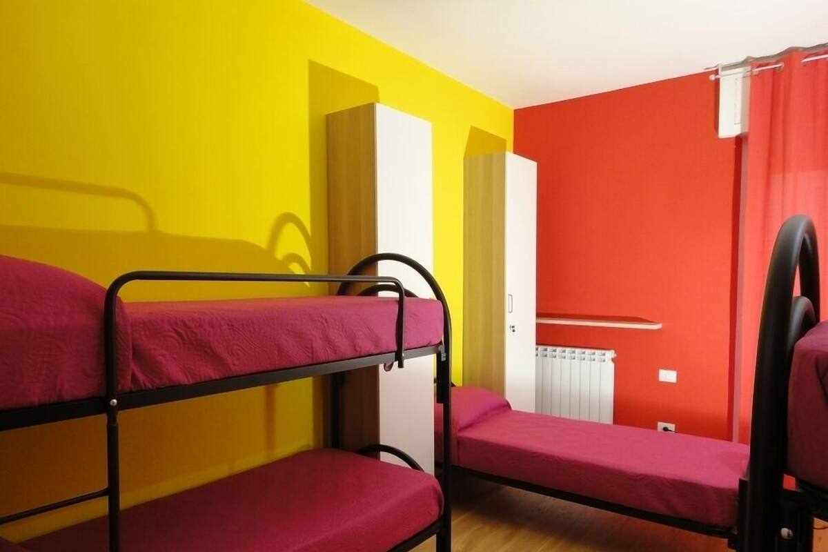 Une chambre de dortoir avec des lits superposés, une armoire blanche et un radiateur.