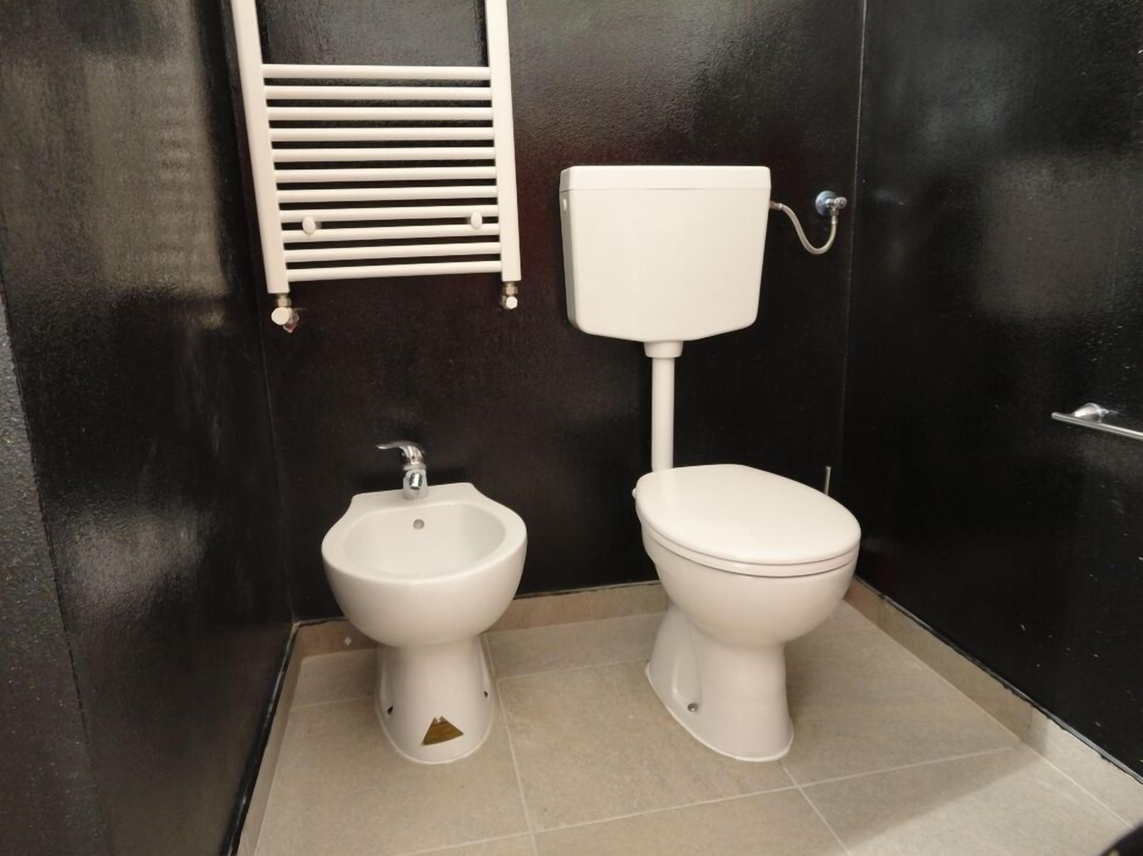 A bathroom with a bidet, toilet, and a towel rack.