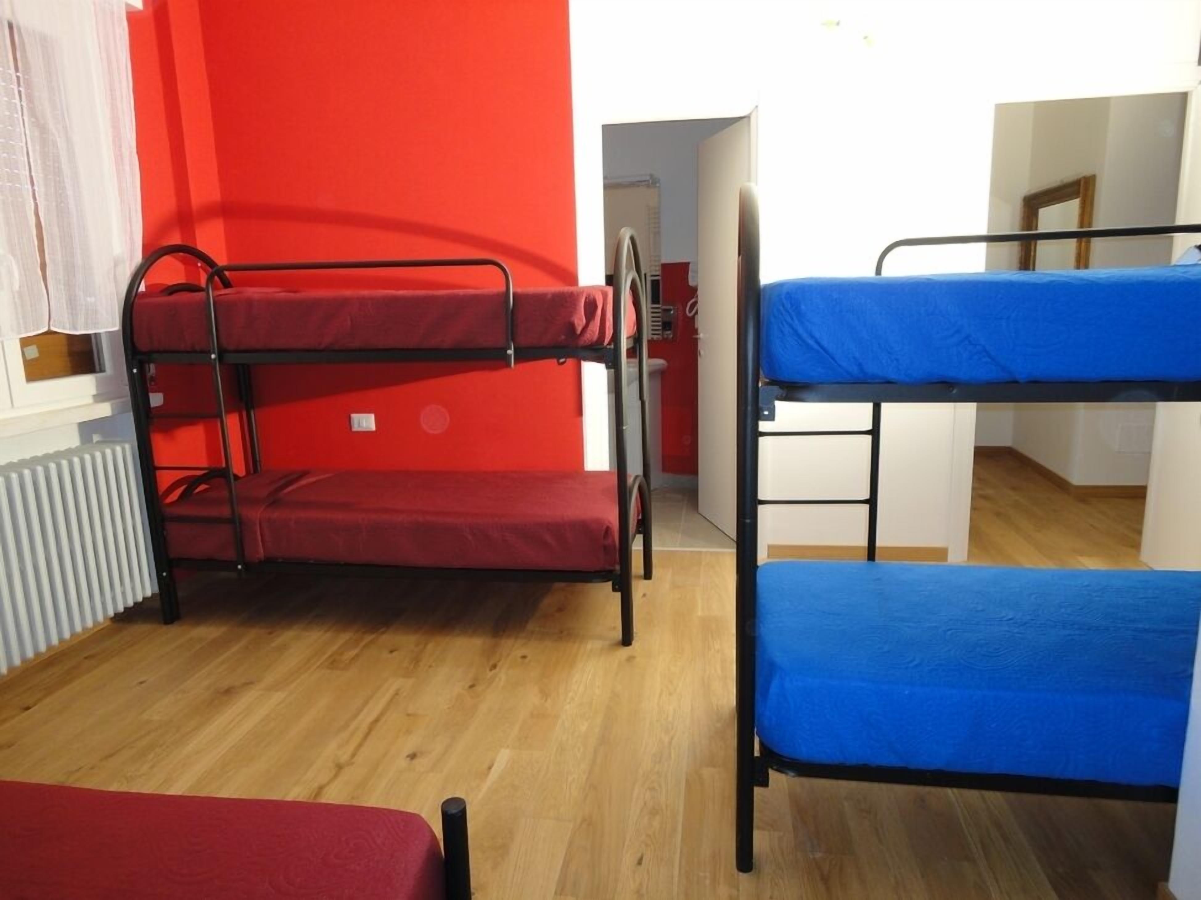 Une chambre de dortoir avec des lits superposés, un plancher en bois et des murs rouges.