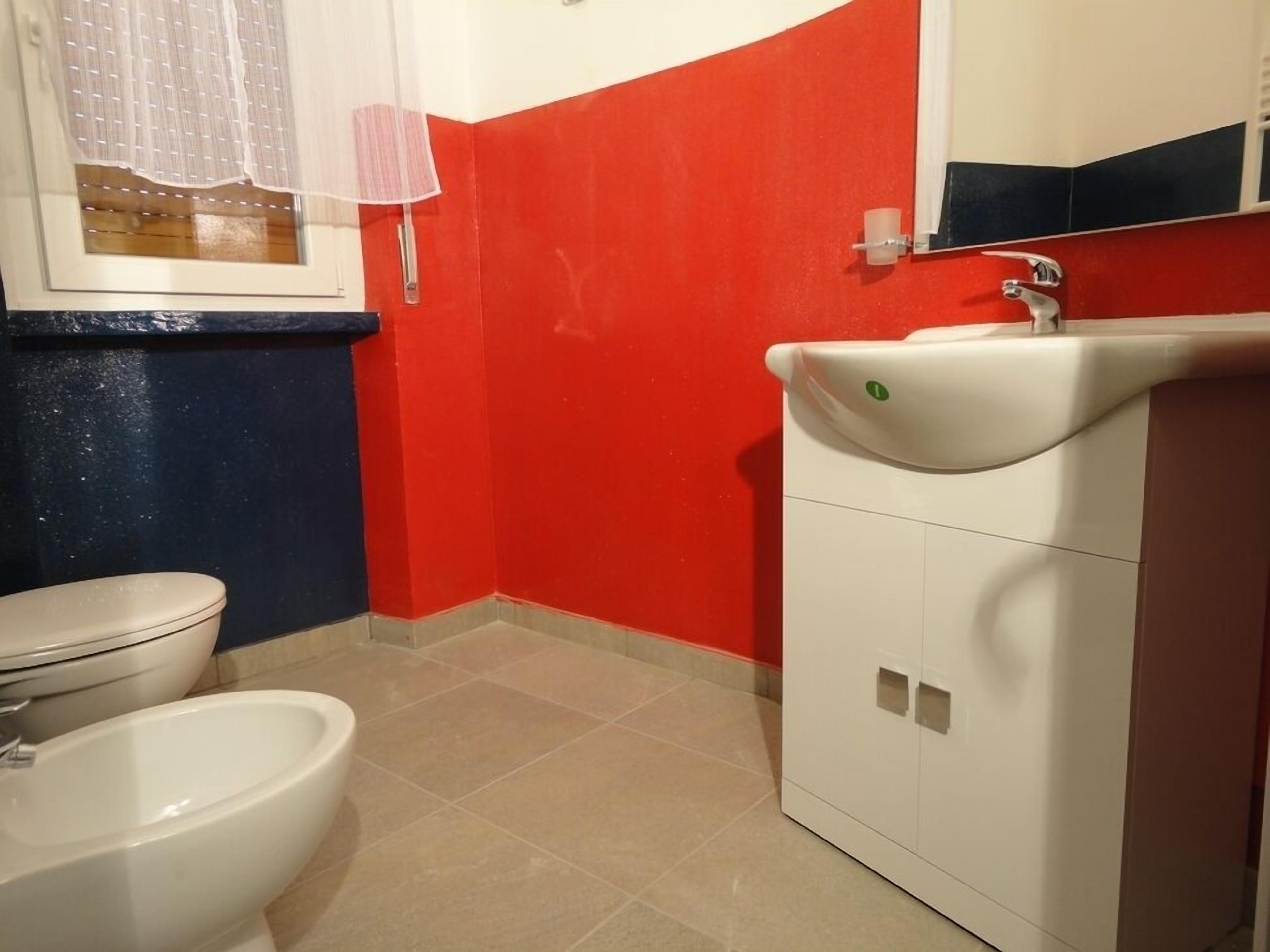 Un bagno con toilette, bidet e lavandino bianco con specchio sopra.