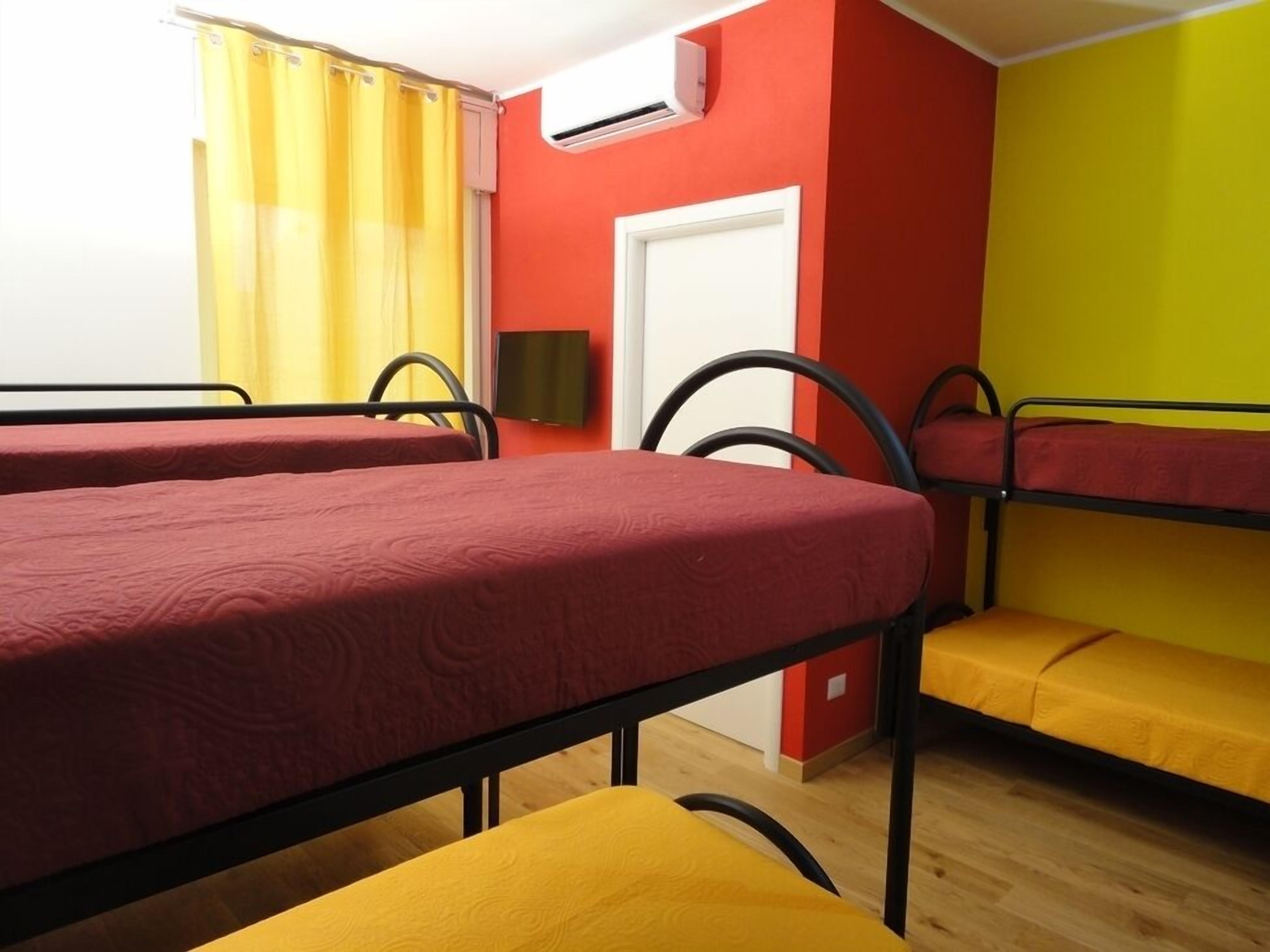 Un dormitorio con literas, una ventana con cortinas amarillas, un equipo de aire acondicionado y una puerta.
