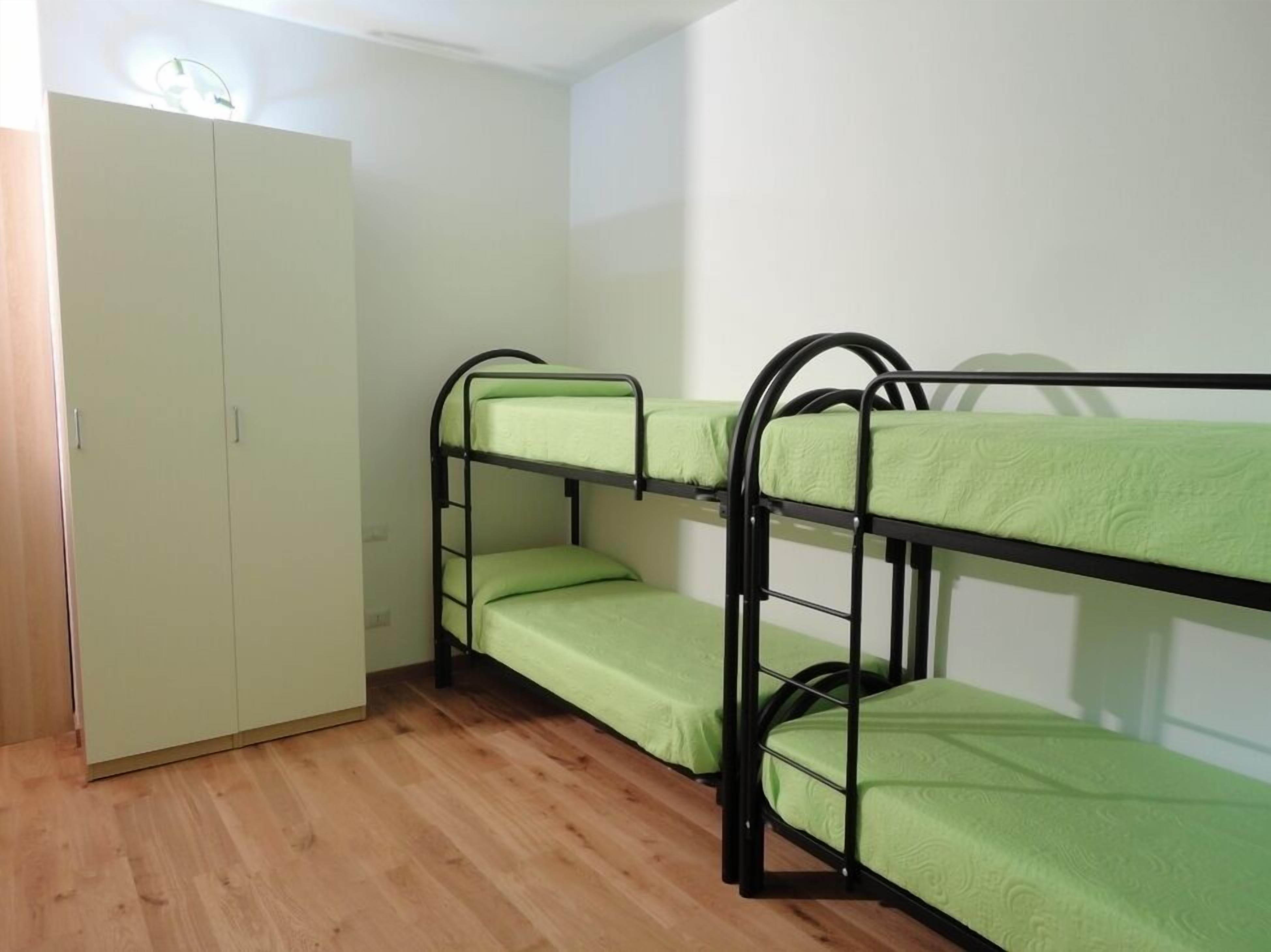 A bunk bed room with a wardrobe and a wooden floor.