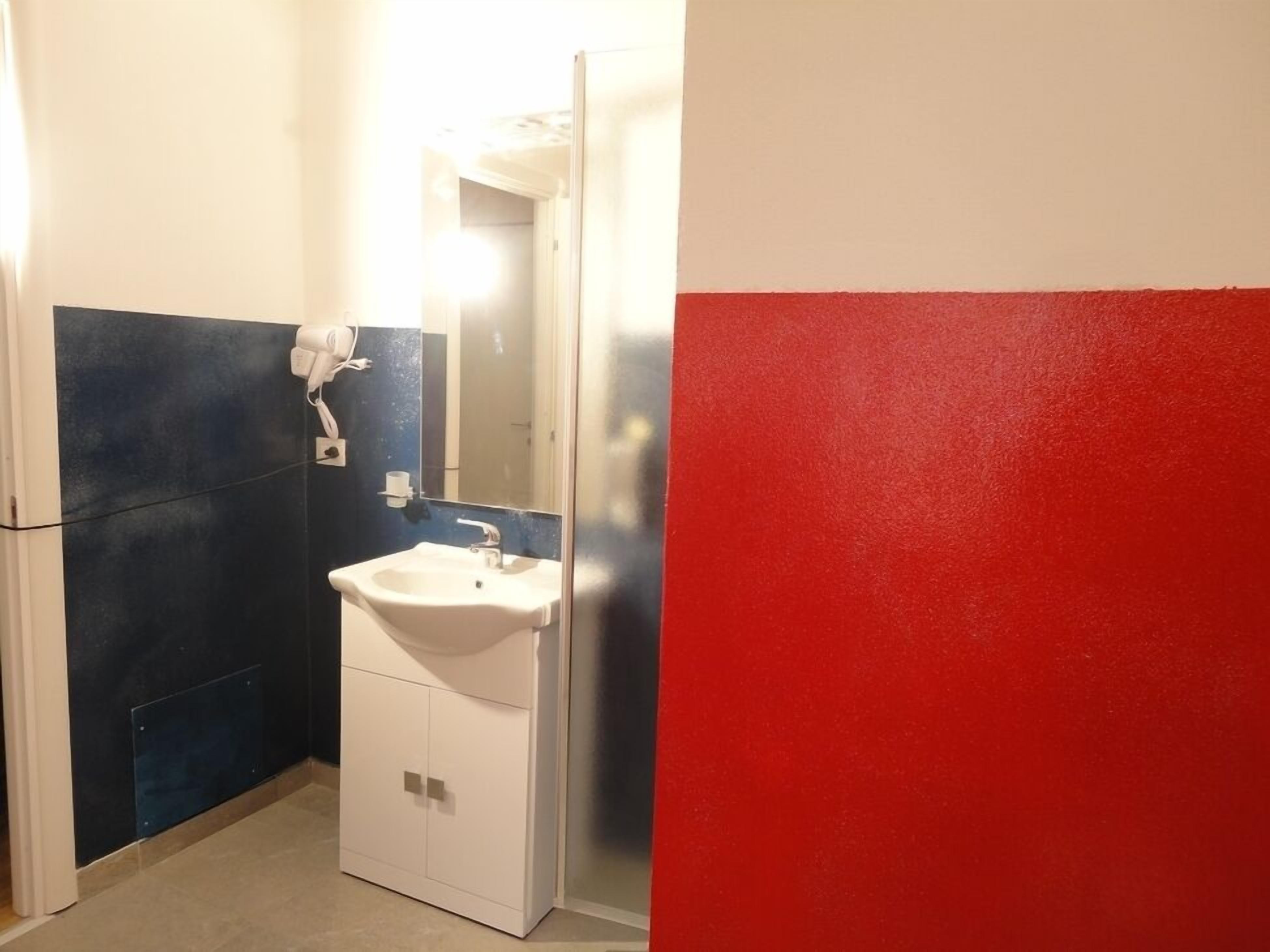 Casa de banho com lavatório branco, dispensador de toalhas e espelho.