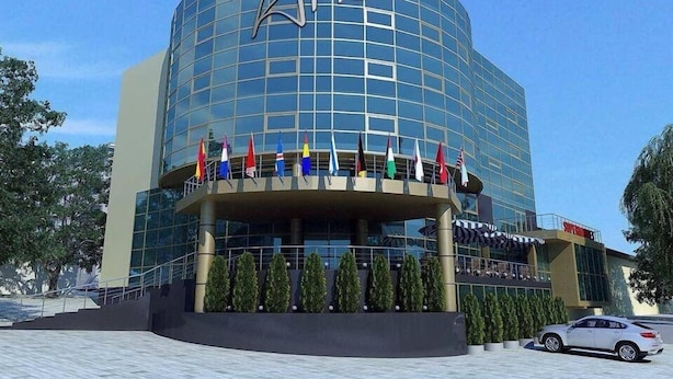A modern hotel with a curved glass facade and a prominent logo. - Aria Hotel Chisinau (Chisinau)