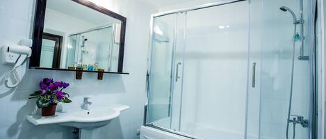 A modern bathroom with a glass-enclosed shower, a white sink, and a mirror above it.