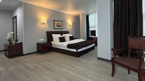 A modern hotel room with a large bed, bedside tables, a desk, and a chair. - Aria Hotel Chisinau (Chisinau)