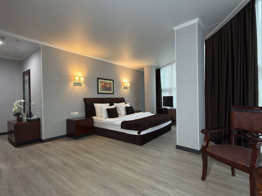 A modern hotel room with a large bed, bedside tables, a desk, and a chair.