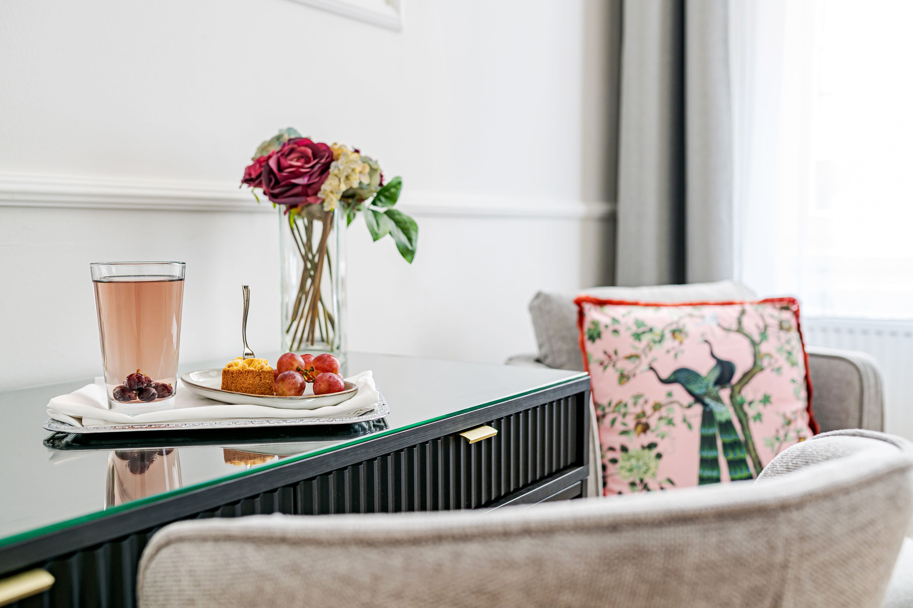 Une table à manger avec un verre, une assiette de nourriture et un vase de fleurs.