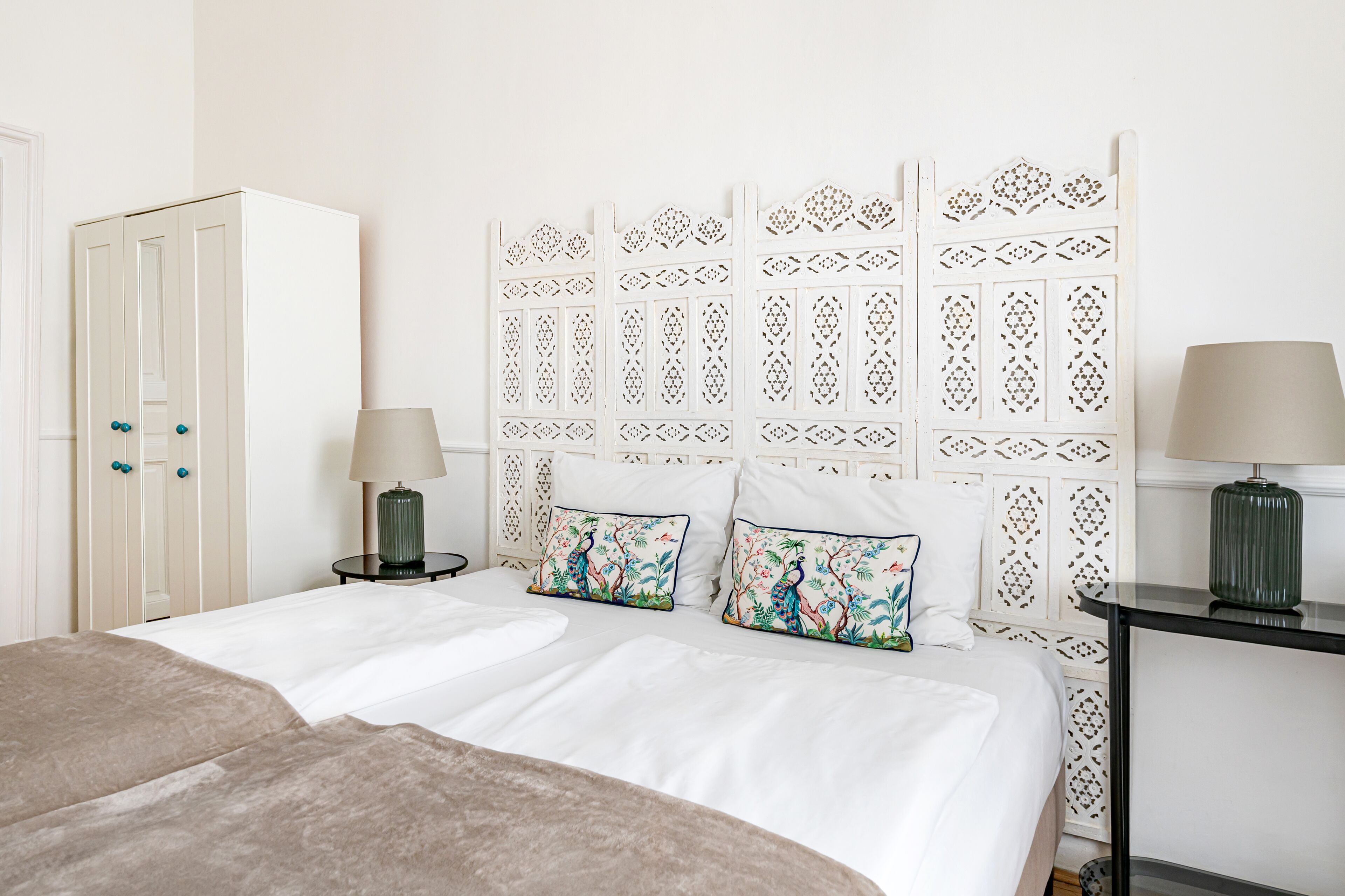 Une chambre à coucher comprenant un lit, deux tables de chevet, une armoire et une tête de lit décorative.