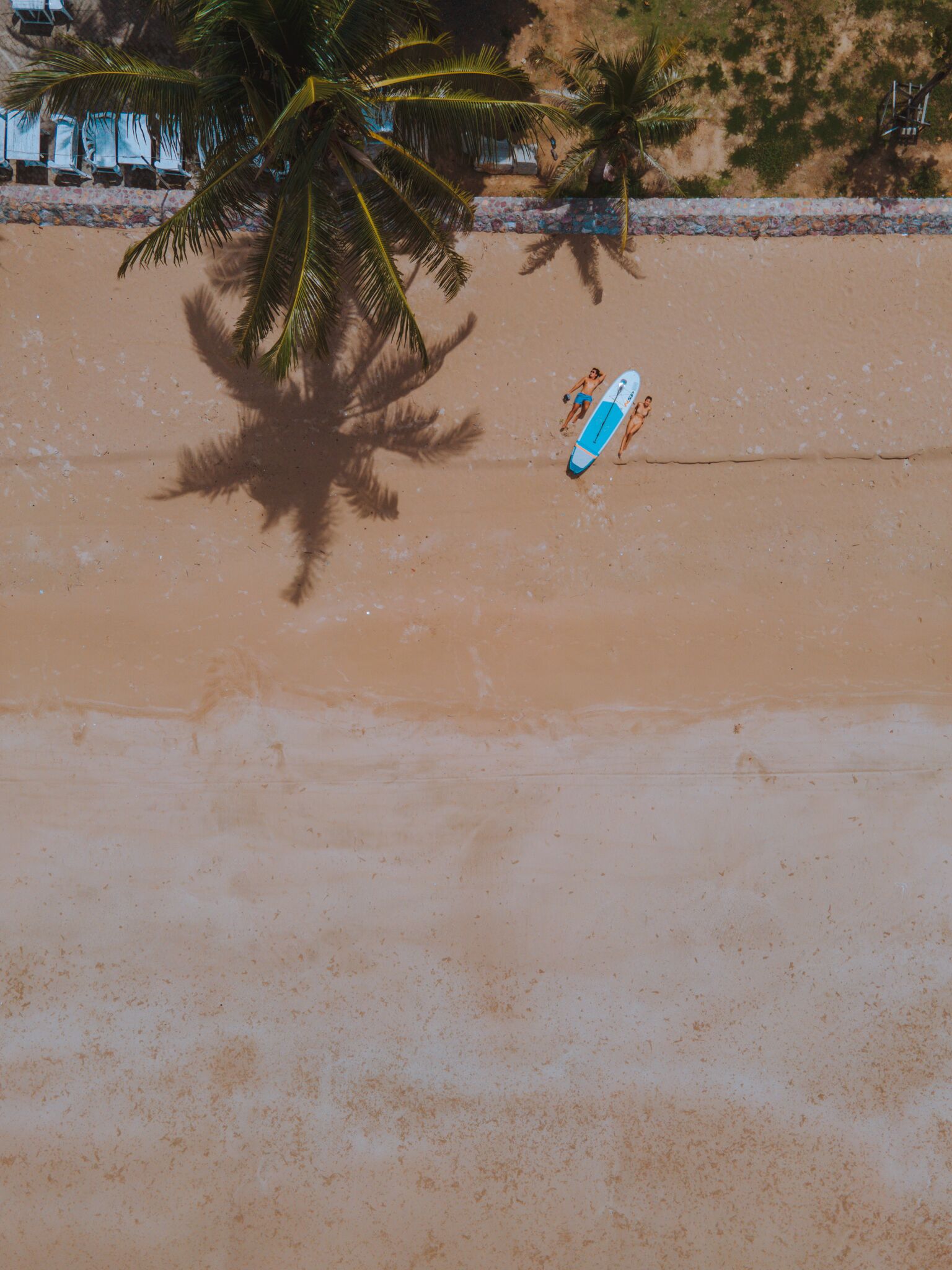 A beach with a surfboard and a person walking.