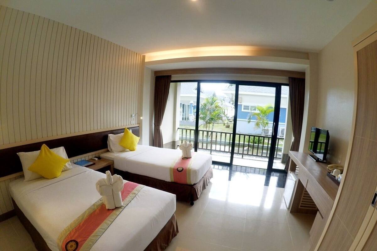 A hotel room with two beds, a TV, a balcony with a view, and a sliding door.