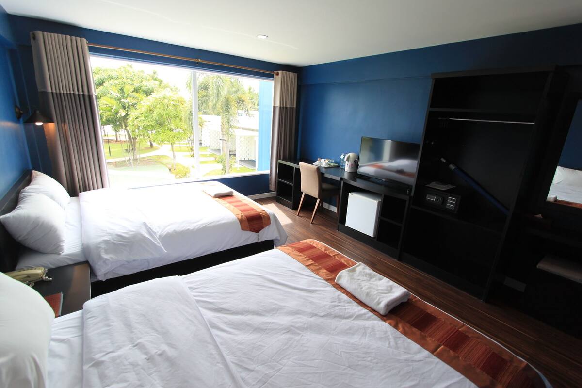 A hotel room with two beds, a desk, a TV, and a wardrobe.