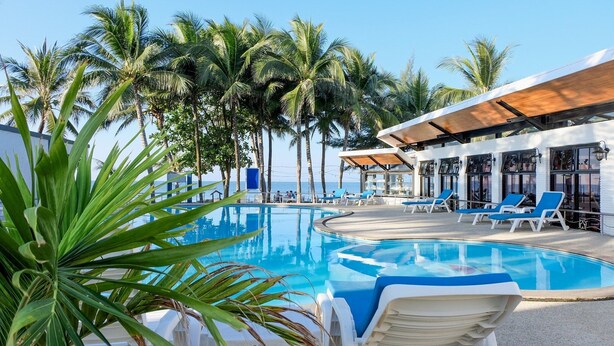 Un espace aménagé au bord de la piscine, avec des chaises longues et une vue sur la mer.