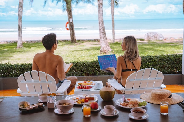 Dos personas sentadas a una mesa con vista a la playa y al océano.