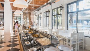 Un espace buffet avec plusieurs stands de nourriture, des chaises et des tables blanches.