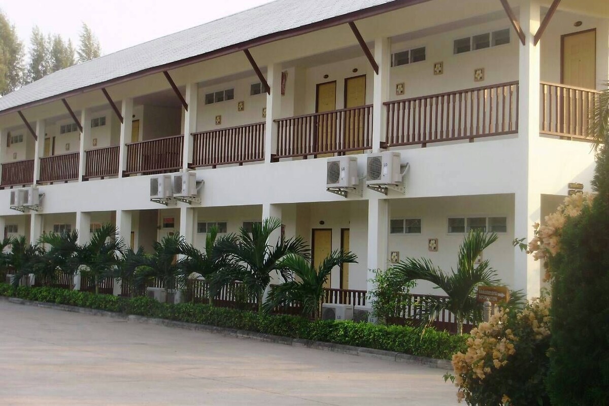 A multi-story hotel with balconies, air conditioning units, and a parking lot.