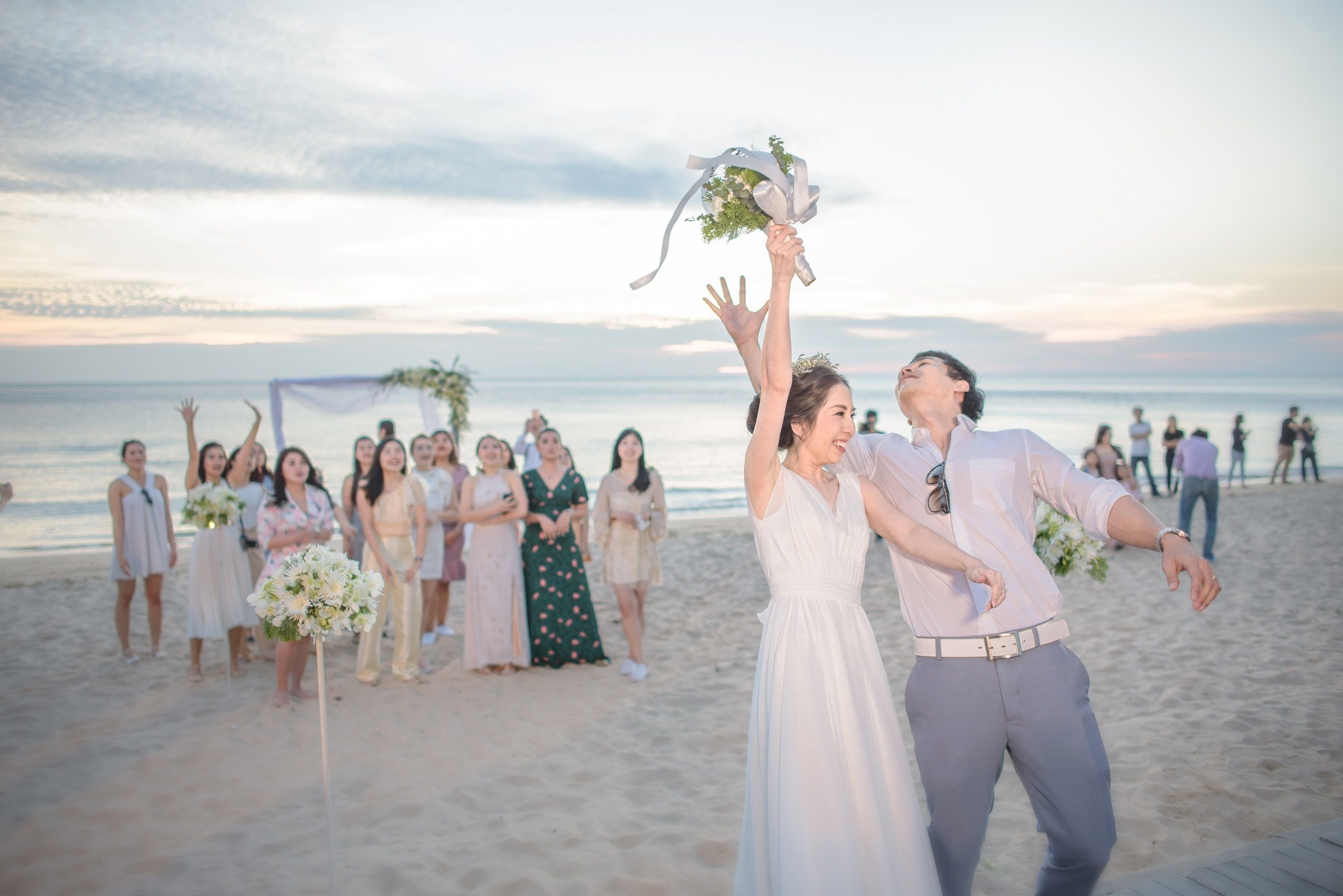 Ceremonia de boda en la playa con invitados y una pareja vestida de novios.