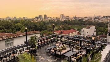 A rooftop terrace with outdoor seating, a view of the city skyline, and a body of water.