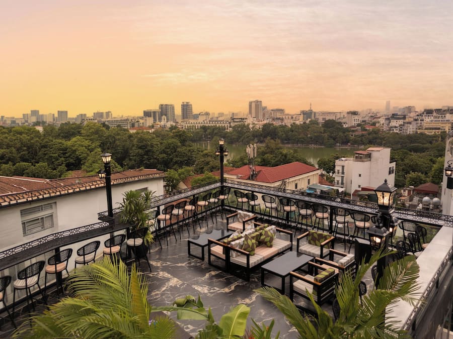 Terraço no telhado com área de estar ao ar livre, vista para o horizonte da cidade e um corpo d'água.