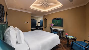 A hotel room with a large bed, a desk, a chair, a television, and a decorative ceiling light fixture.