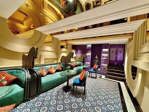 A luxurious lounge area with a patterned floor, seating with cushions, and a staircase leading to a purple room. - Hôtel Le Joyau Bleu Hanoï (Hanoi)