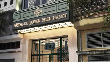 Entrada de un hotel con un letrero que dice 'HOTEL LE JOYAU BLEU HANOI'.