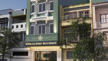 Un hotel con una entrada destacada, un balcón y un letrero que indica el nombre del hotel.