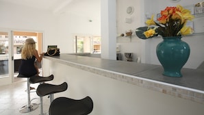 A modern kitchen with a bar area, a large vase with flowers, and a view of the outside. - Résidence Lago Verde (Porto-Vecchio)