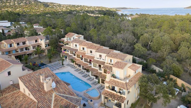 A resort with multiple buildings, a swimming pool, and a view of the sea. - Résidence Lago Verde (Porto-Vecchio)