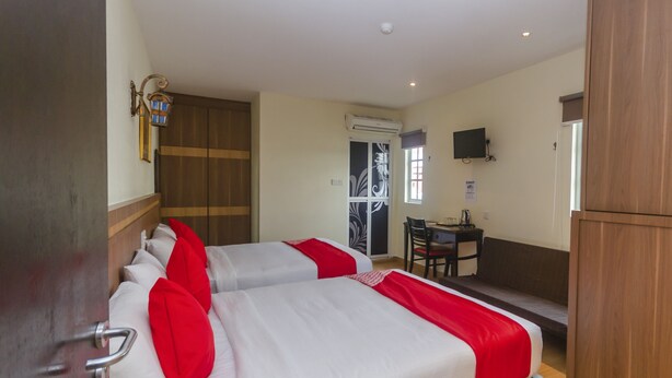 A hotel room with two beds, a desk, and a TV.