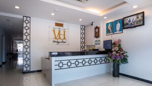 A hotel reception area with a reception desk, a clock, a welcome sign, and a framed picture on the wall.