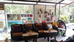 A cozy seating area with wicker furniture, a small table with a vase, and a wall decorated with various items and pictures. - Nan inn Bungalow (Karon)