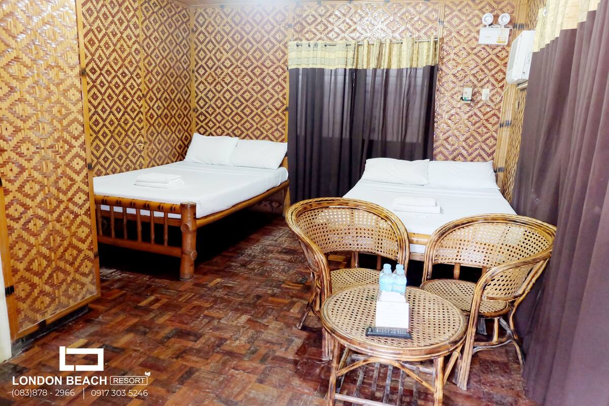 Une chambre avec deux lits simples, une petite table avec des chaises et un mur décoré de motifs.