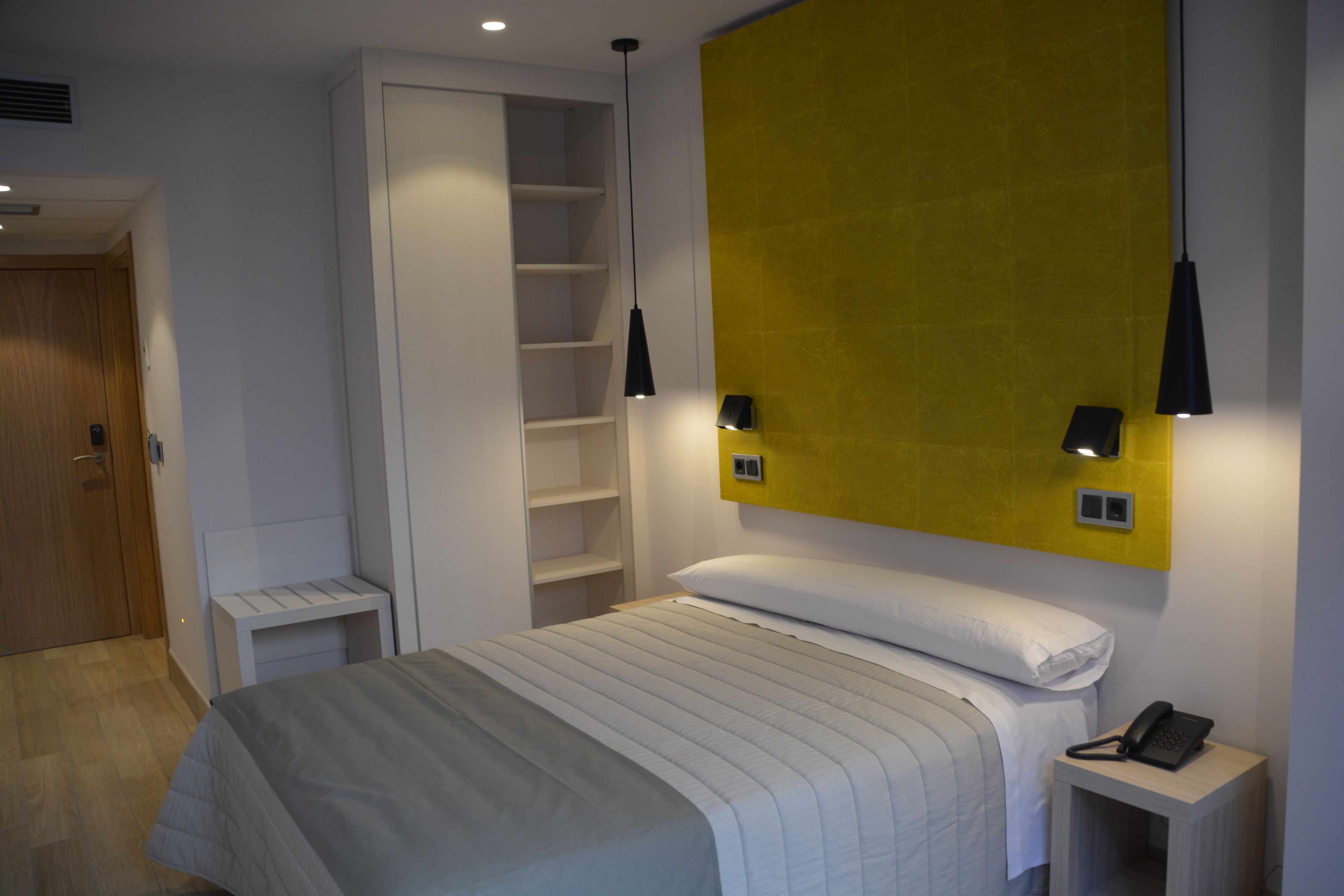 Un dormitorio moderno con cama, mesita de noche y armario empotrado.