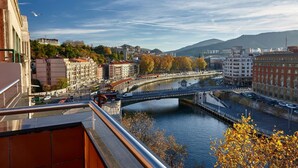 A river with a bridge, buildings, and a mountainous backdrop.