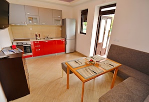 A compact kitchen with modern appliances, a dining area with a table set for two, and a sofa in a living space.