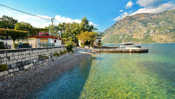 A waterfront property with a stone wall, clear water, a dock, and a mountain in the background. - Step to Kotor bay Stoliv (Donji Stoliv)