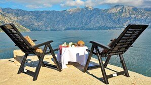Two lounge chairs facing a lake with a mountain backdrop. - Step to Kotor bay Stoliv (Donji Stoliv)