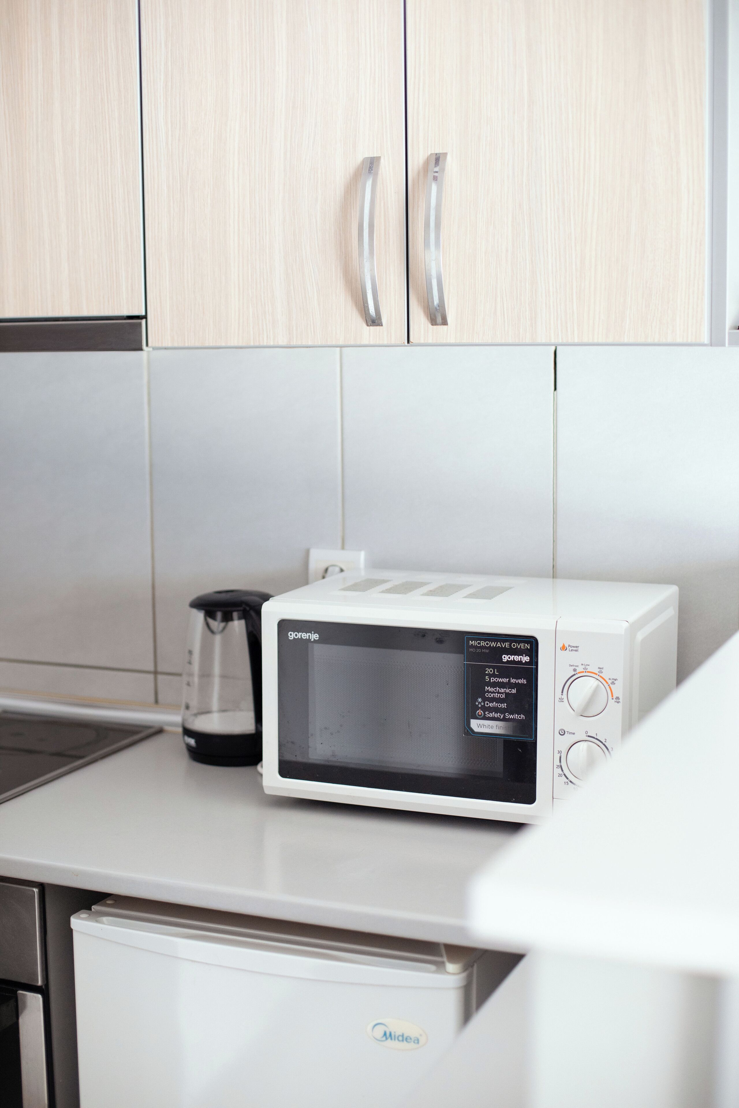 A microwave oven on a kitchen counter with a coffee maker beside it.