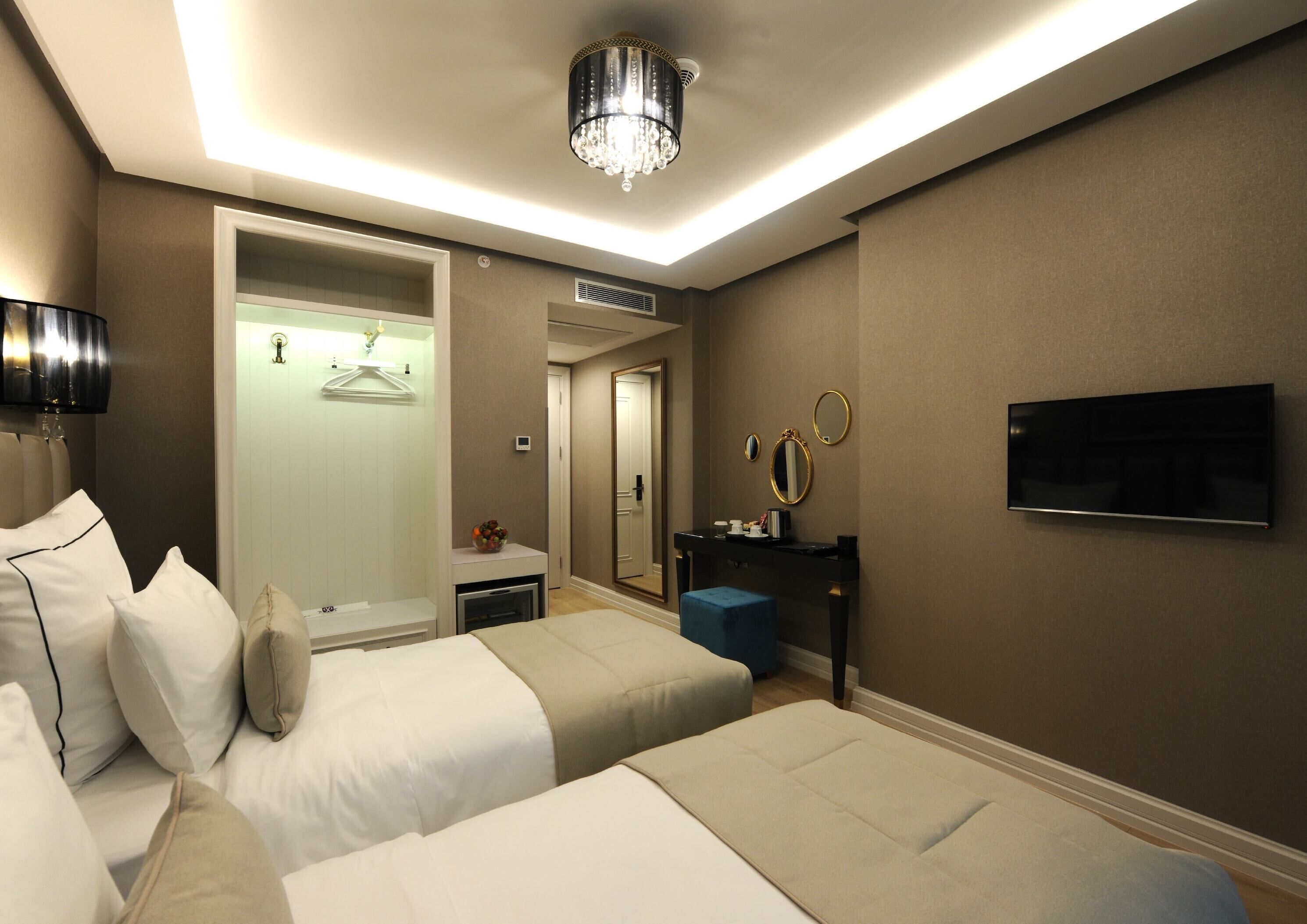 Een hotelkamer met twee bedden, een televisie, een spiegel en een wastafel met een aanrecht.