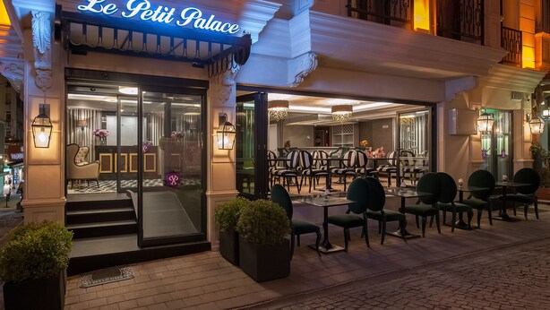 An outdoor seating area with tables and chairs, a well-lit entrance, and a sign reading "Le Petit Palais". - Le Petit Palace Hotel (Istanbul)