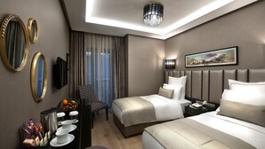A modern hotel room with two beds, a desk with a lamp, a chair, and a large window with curtains. - Le Petit Palace Hotel (Istanbul)